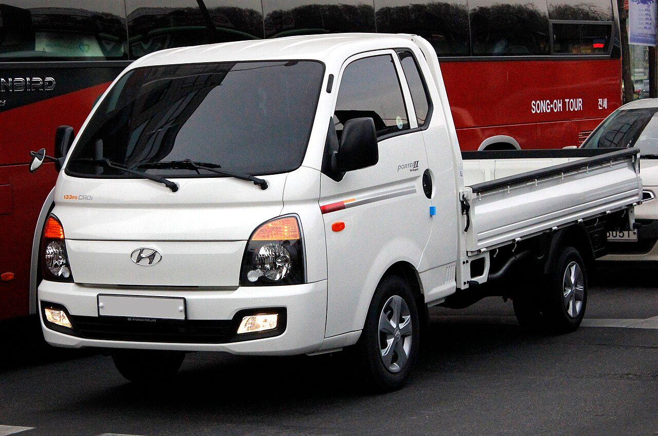 Hyundai Porter: Porter blanco con caja de barandas, vista delantera de tres cuartos